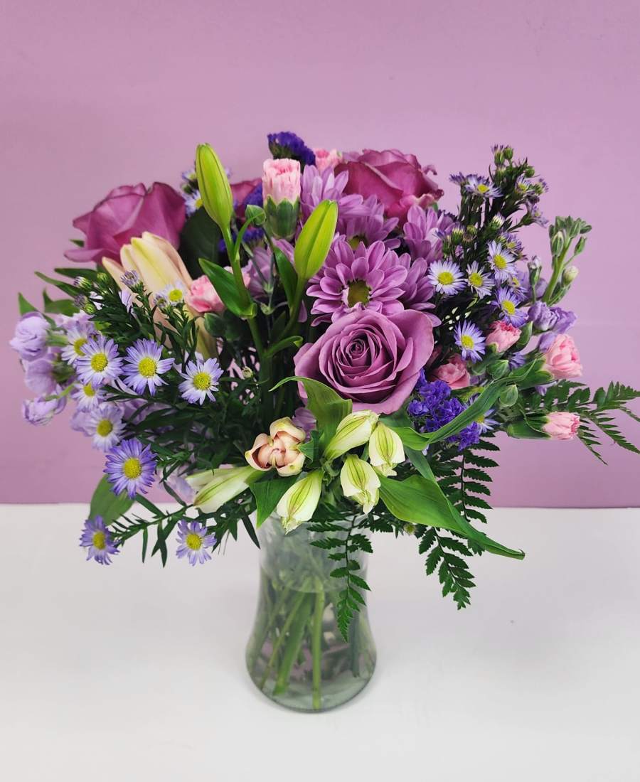 Purple and pink mixed bouquet in a clear glass vase