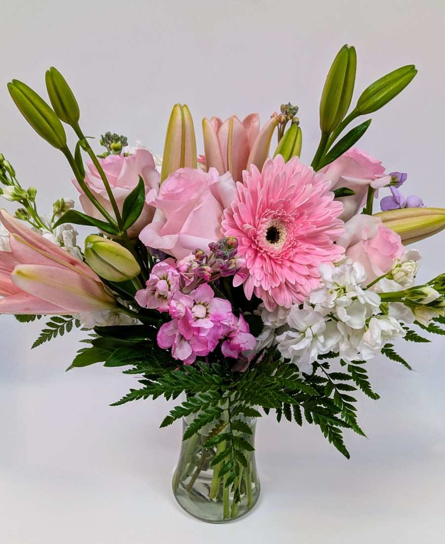 A soft bouquet of pink and white blooms arranged in a clear glass vase