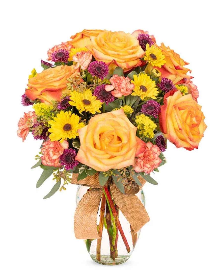 Bouquet of yellow roses, daisies and pink carnations in a glass vase