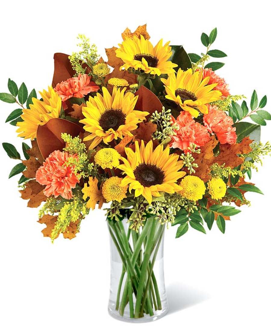Sunflower and orange carnation bouquet in a clear glass vase
