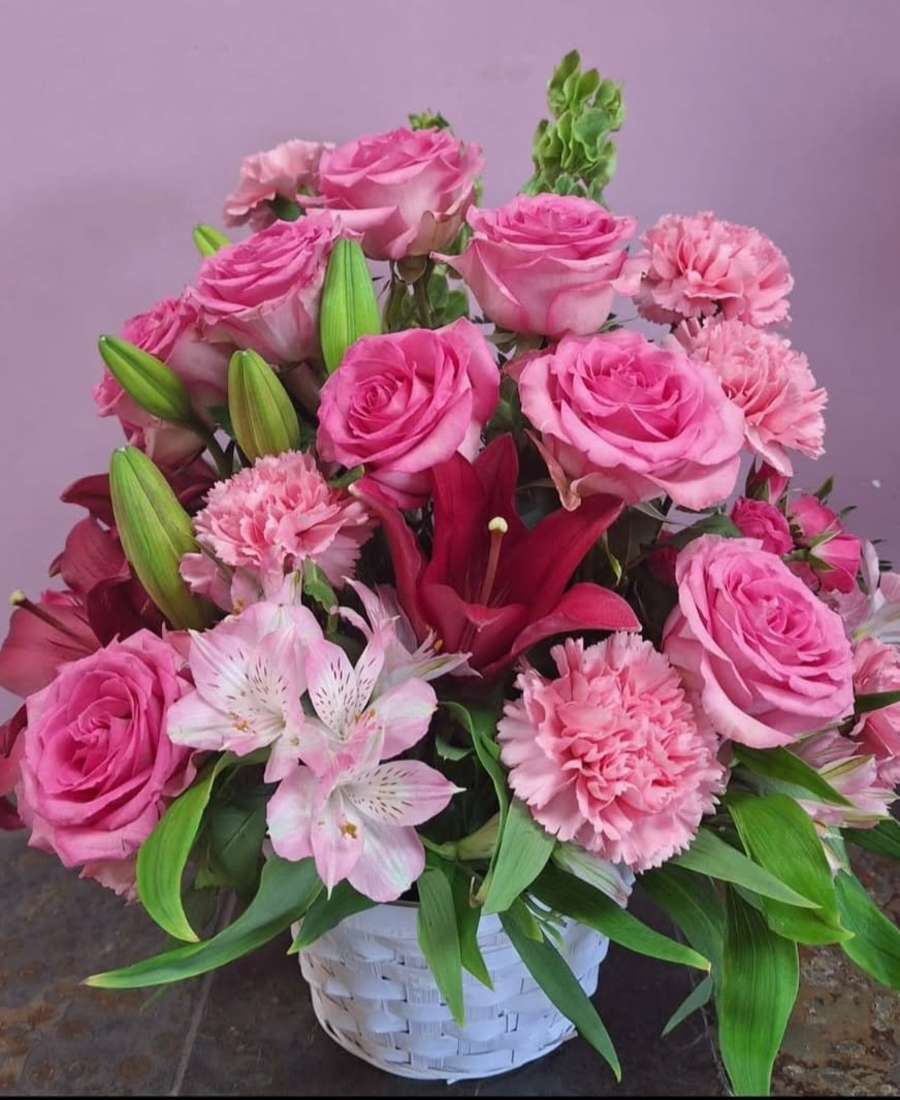 Pink roses and lilies arranged in a white basket